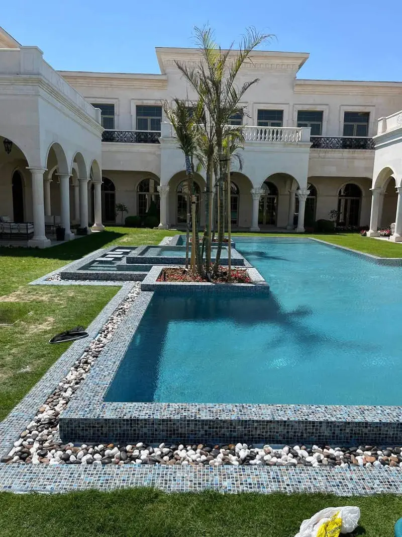 مسبح مكسوّ بموزاييك زجاجي أزرق بحافة من الحصى